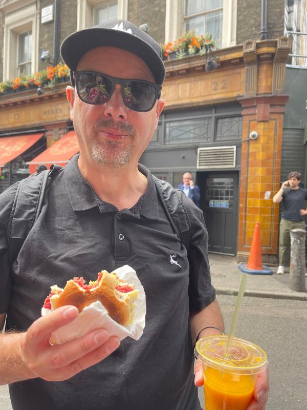 Man holding a sandwich and a plastic cup of juice.