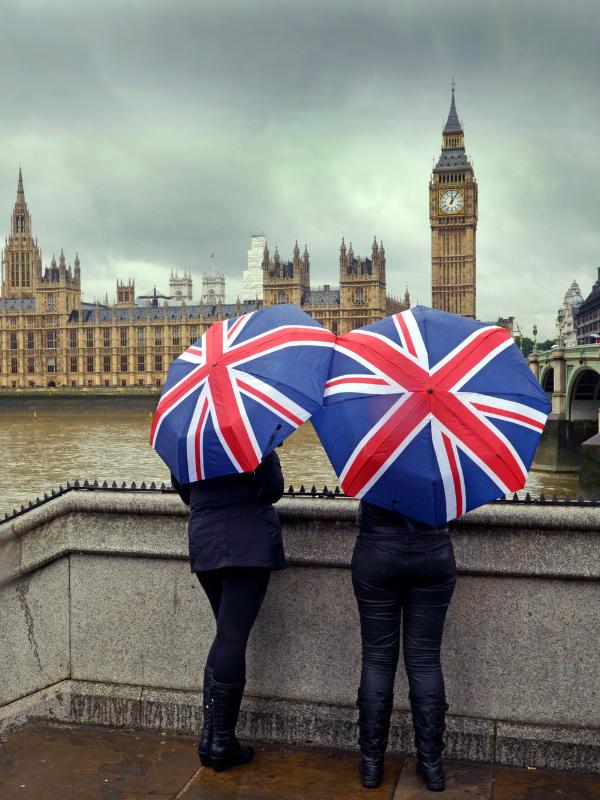 2 people holding umbrellas in front of Big ben.