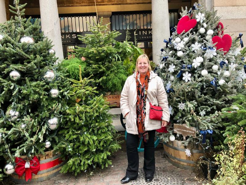 Woman surrounded by Christmas trees.