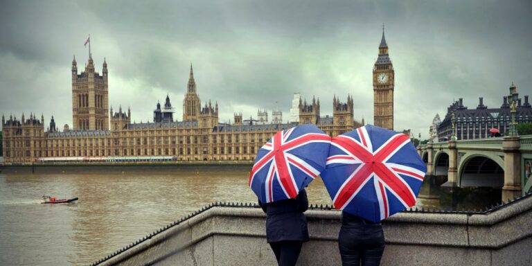 London in February two ladies standing with umbrellas with Westminster behind them.