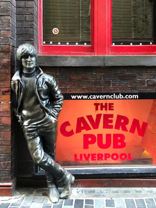 Statue of John Lennon next to a sign for the Cavern Club in Liverpool.