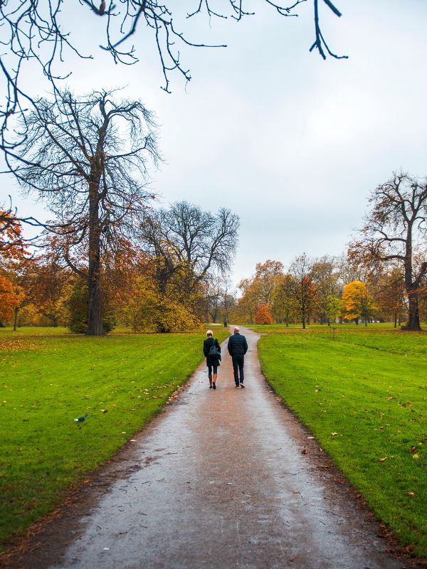 Two people walking across a path on an autumn day in London.