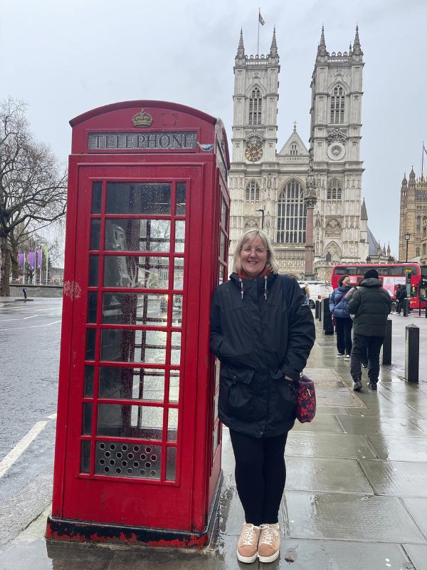 a woman standing next to a red telephone booth