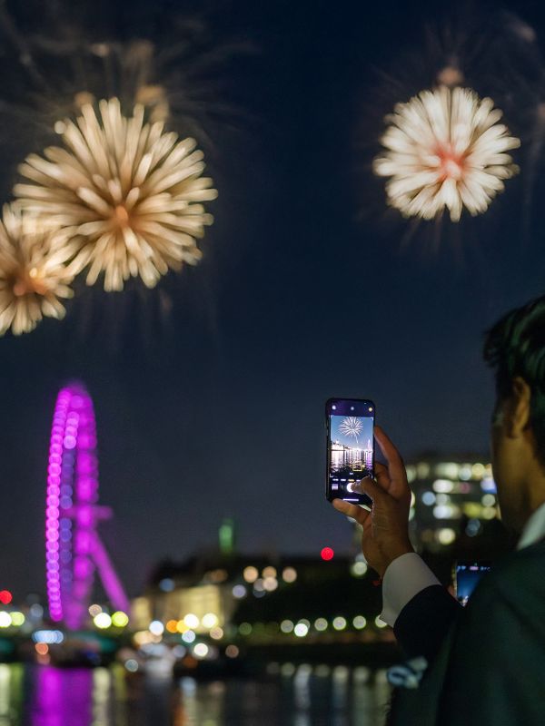 A passenger on a City Cruises boat photographing the New Year's Eve fireworks over the London Eye.