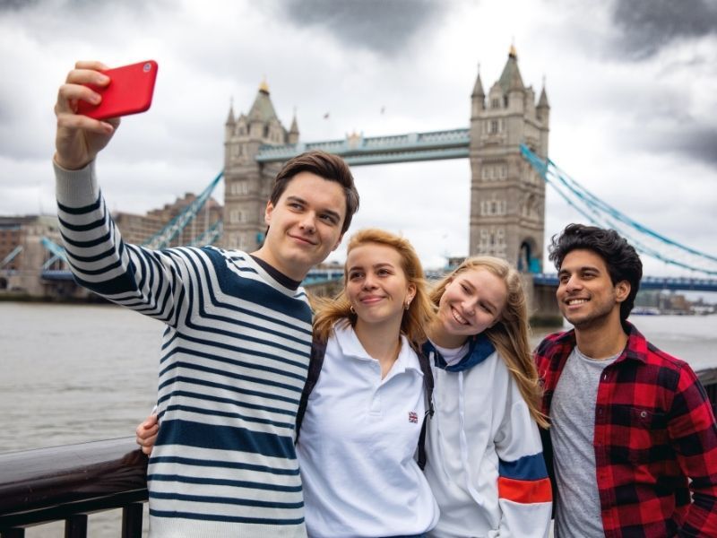 Teenagers posing for a selfie in front of Tower Bridge - London with teens.