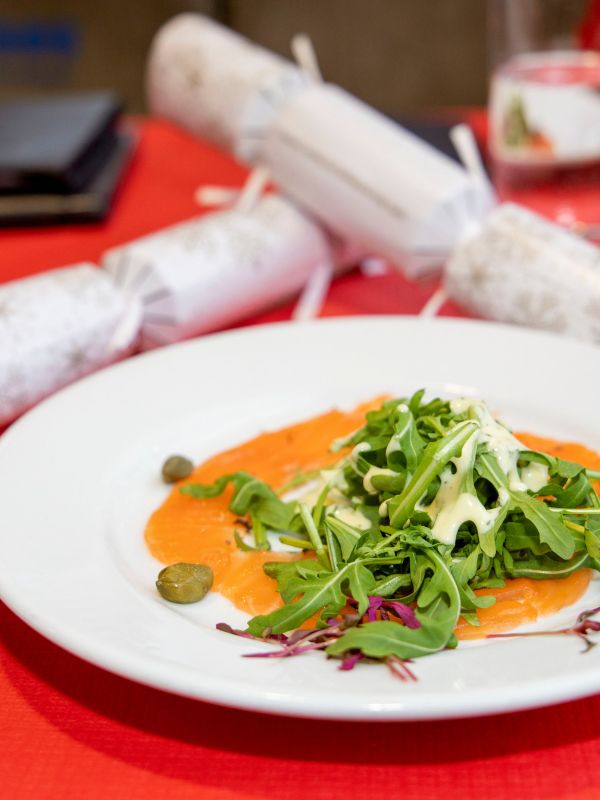 Smoked salmon starter and Christmas crackers on a red tablecloth aboard a City Cruises Christmas lunch cruise.