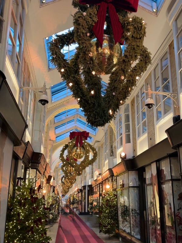 Giant wreaths with red bows and mirror balls hanging the length of Burlington Arcade.