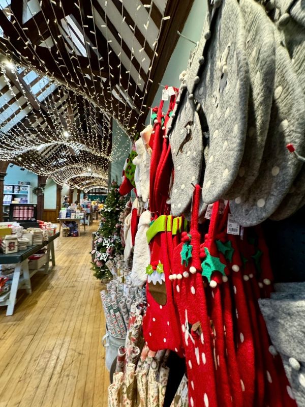 Fairy lights strung across the beamed ceiling of the Christmas shop inside Liberty, with stockings hanging in the foreground.