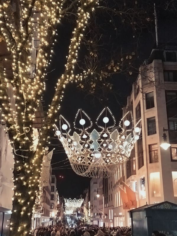Illuminated crown Christmas lights above New Bond Street with trees wrapped in fairy lights.