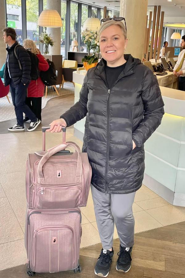 A lady with 2 pink suitcases.