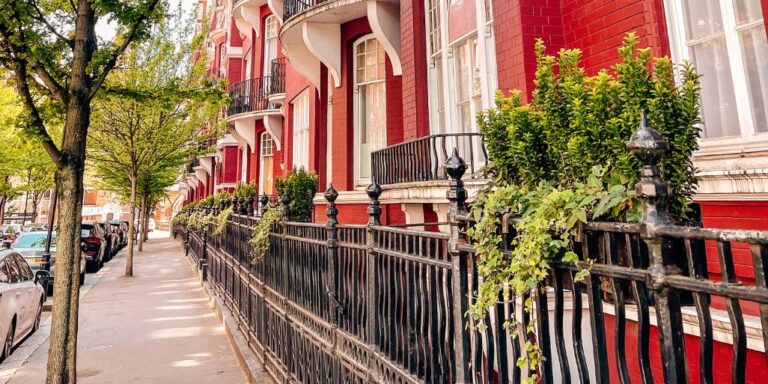 A tree-lined street of red brick townhouses in Chelsea, London in spring