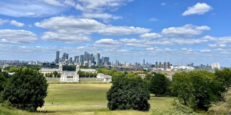 View from the hill in Greenwich Park on a sunny summer day, looking across to the Old Royal Naval College and the Canary Wharf skyline beyond