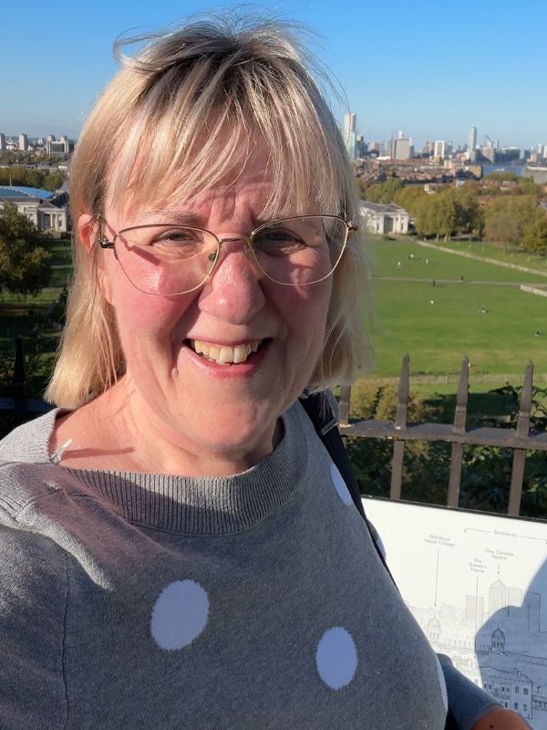 Tracy from London Travel Planning at the Greenwich Park viewpoint looking over the Old Royal Naval College and Canary Wharf on a sunny October day