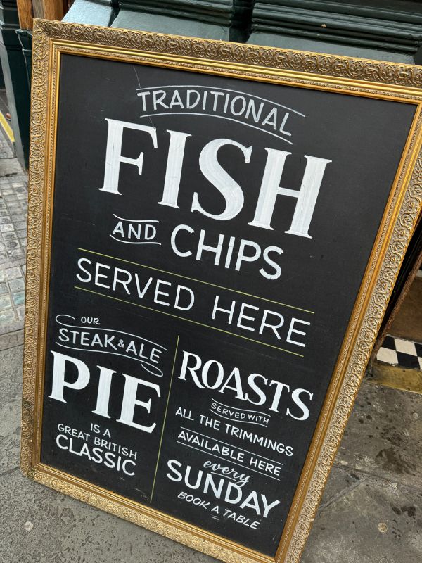 A traditional pub A-board in London advertising fish and chips, steak and ale pie and Sunday roasts