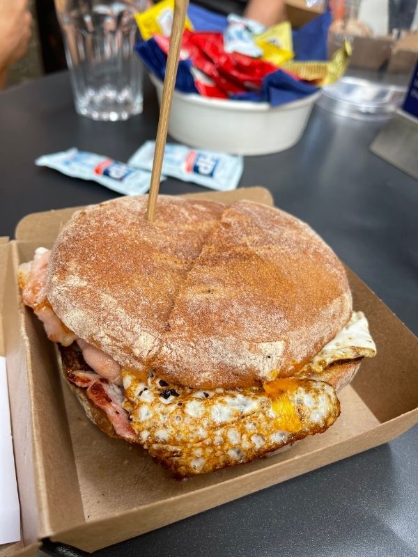 Bacon and fried egg breakfast roll in a cardboard tray at a Southwark cafe