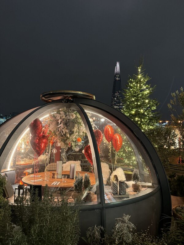 Coppa Club igloo at Tower Bridge decorated for Christmas with a lit tree and The Shard behind