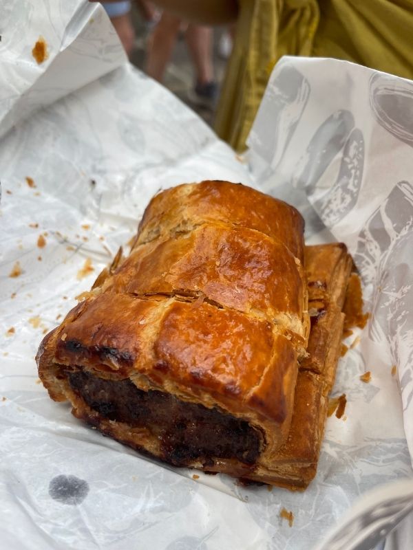 Golden flaky sausage roll on greaseproof paper at Borough Market