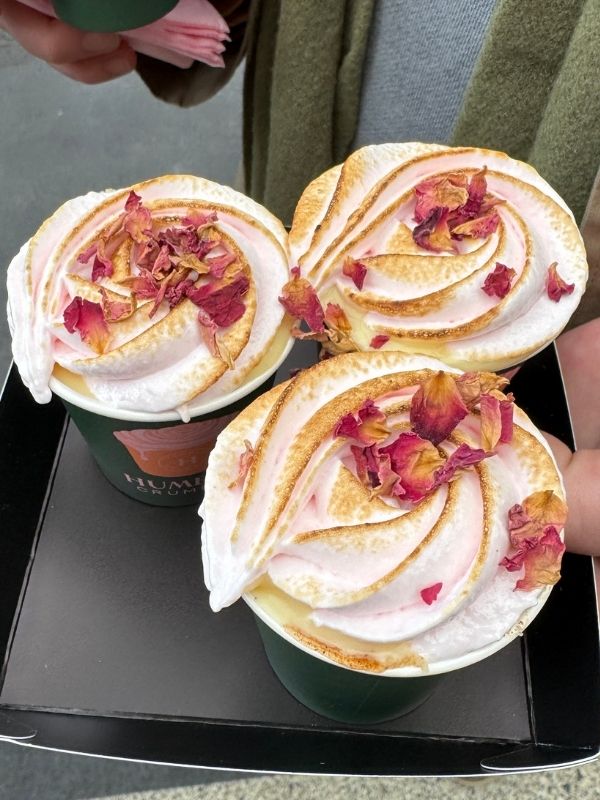 Three crumble pots topped with swirled pink toasted meringue and dried rose petals