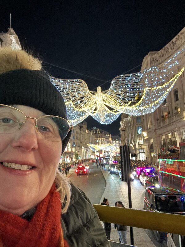 Tracy Collins under the Regent Street Christmas angel lights on an open top bus in London in November