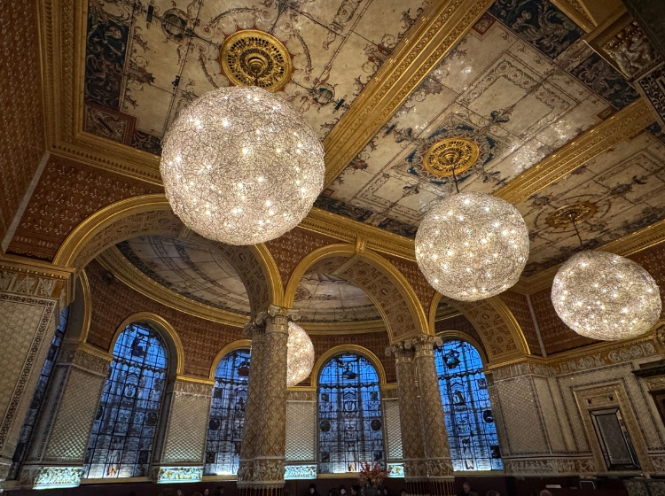 Ornate Victorian cafรฉ at the V&A, with stained glass windows and large globe lights