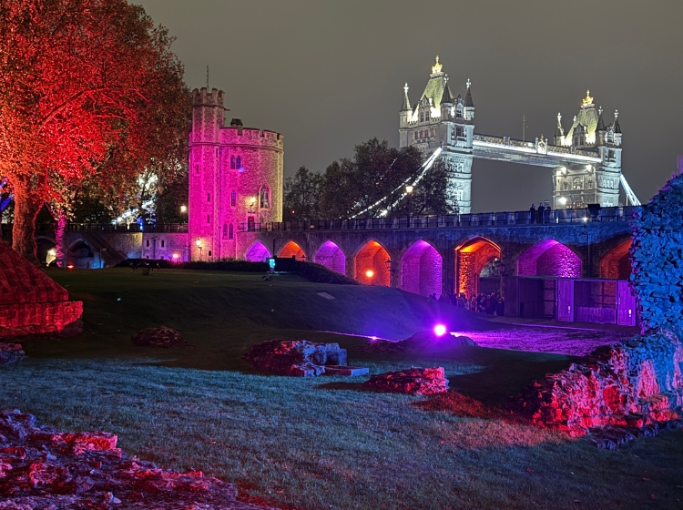 the Tower of London lit up at night with Tower Bridge behind