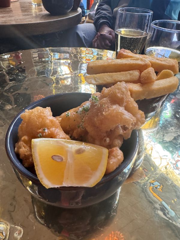 Battered fish and chunky chips with lemon on a polished brass pub table