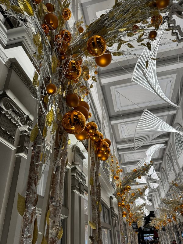 White birch trees hung with gold baubles inside Burlington Arcade at Christmas.