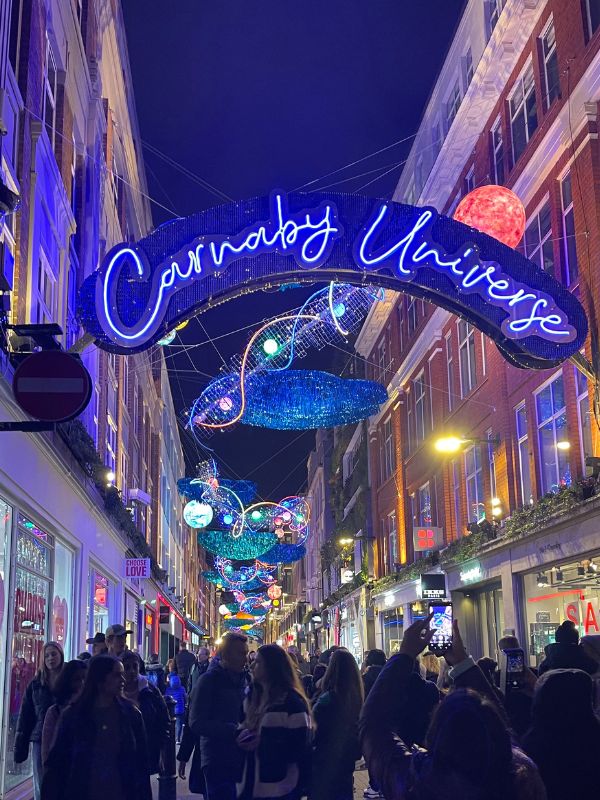 The Carnaby Universe Christmas lights arching over Carnaby Street, with planets and shooting stars above the crowds.