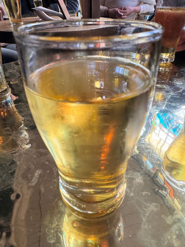 A half pint of cider on a brass pub table