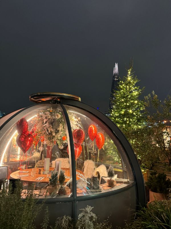 A Coppa Club igloo dressed for Christmas with a lit tree and the Shard behind.