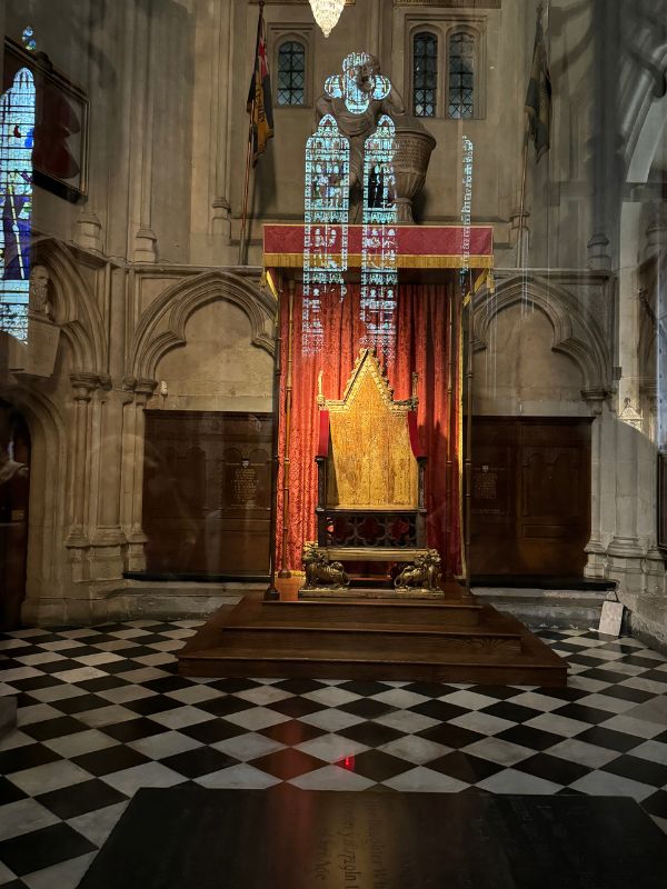 The Coronation Chair on its platform under a red canopy inside Westminster Abbey