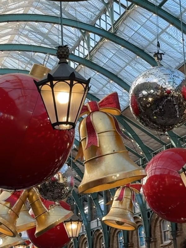 Gold bells, red baubles and mirror balls hanging beside the lanterns in Covent Garden market.