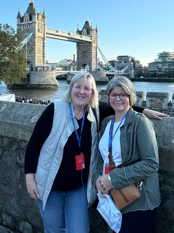 Tracy and Melissa on the Tower of London battlements with Tower Bridge behind
