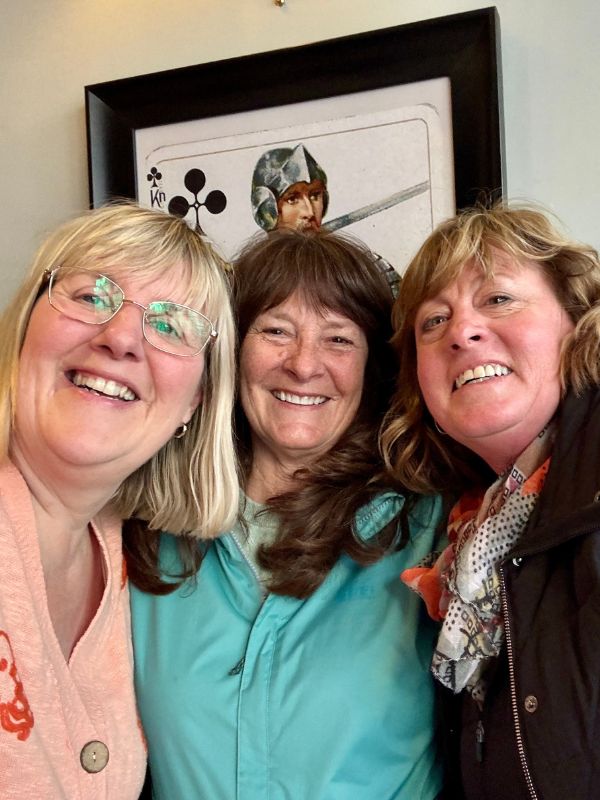 Tracy laughing with two friends beneath framed antique playing cards on the historic pub tour