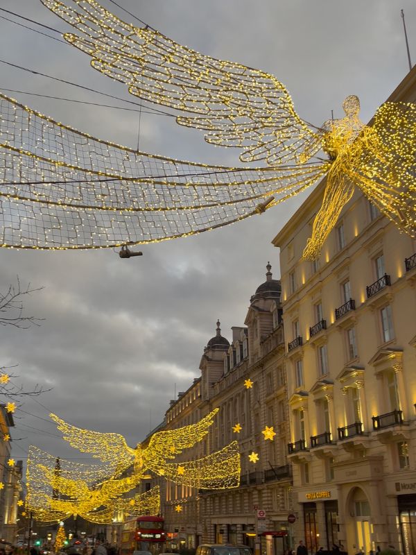 The Spirit of Christmas angel lights in gold above Regent Street at night.