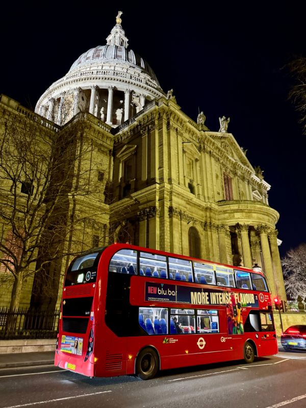 St Paul's Cathedral at night with a red London bus passing