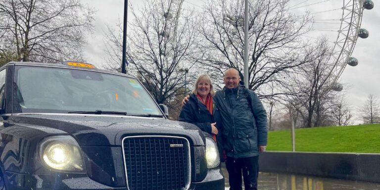 Tracy and Doug in London in the rain in front of the London Eye and beside a London cab